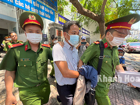 Cảnh sát áp giải ông Huy rời trụ sở CDC Khánh Hòa