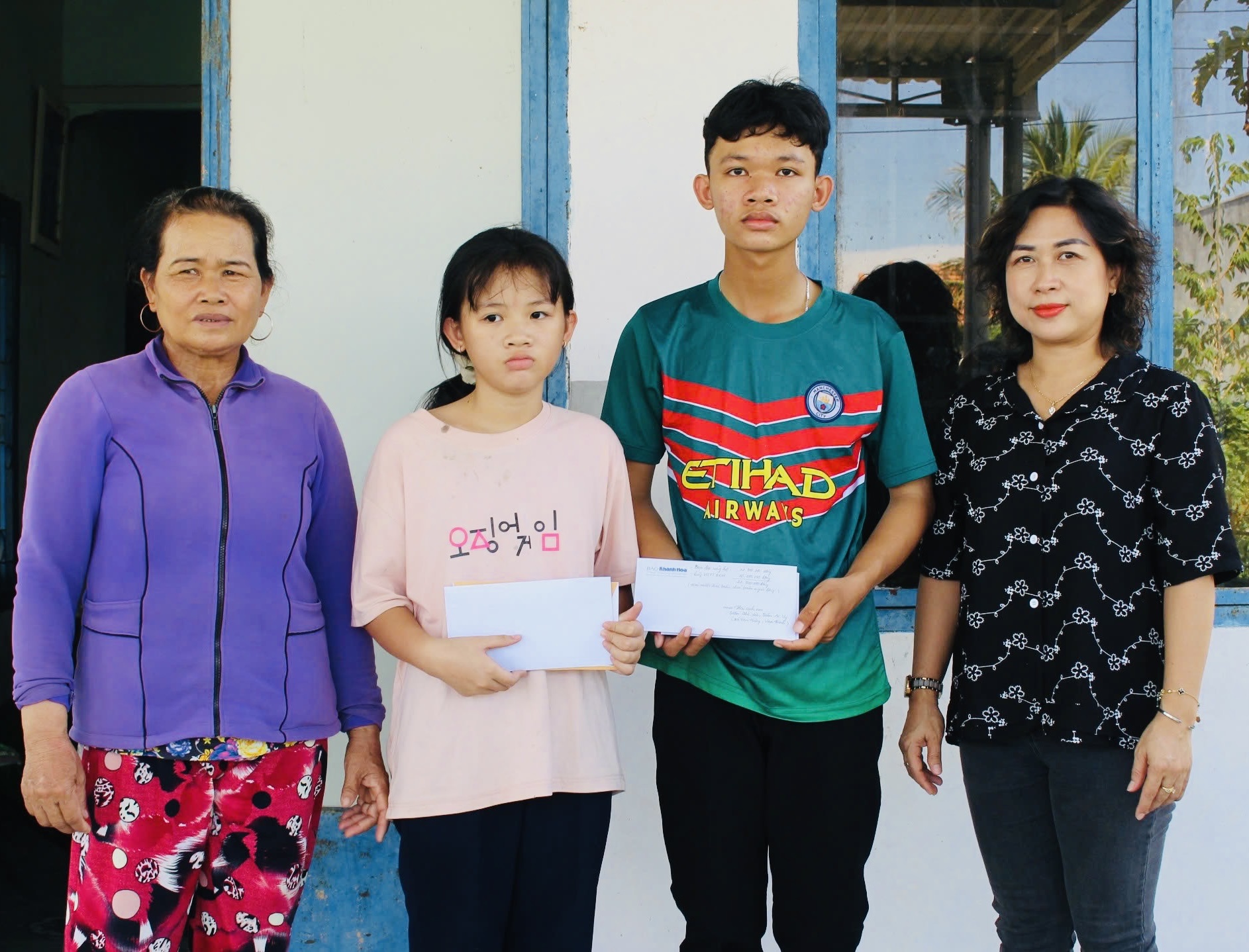 Đại diện Báo Khánh Hòa trao tiền ủng hộ của bạn đọc cho 2 anh em Trần Thế Văn và Trần Ái Vy.
