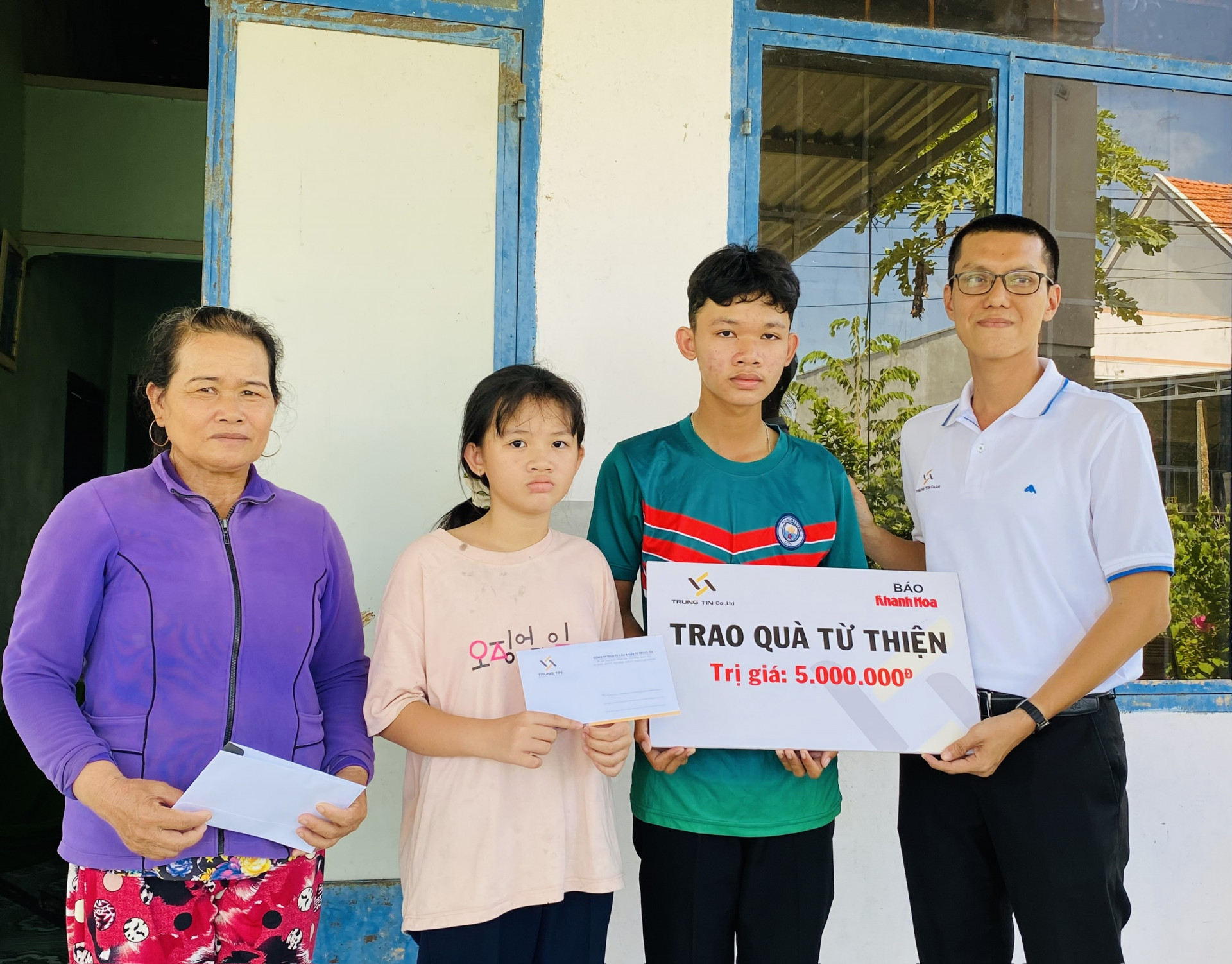 Ông Đỗ Nguyễn - Phó Giám đốc Công ty TNHH Tư vấn và Đầu tư Trung Tín trao tiền ủng hộ cho 2 anh em Trần Thế Văn và Trần Ái Vy